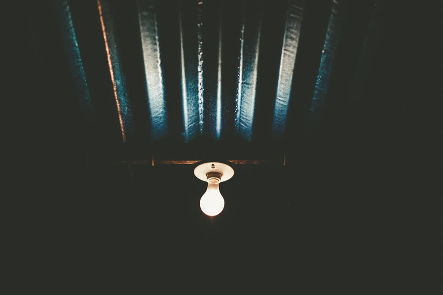 A shining lightbulb on a dark ceiling